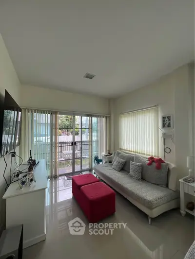 Bright living room with modern decor and large windows leading to a balcony.