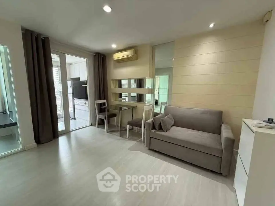 Modern living room with sleek sofa and dining area, adjacent to a stylish kitchen.