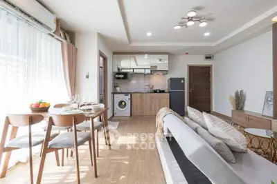 Modern open-plan living room with dining area and kitchen, featuring stylish furniture and natural light.