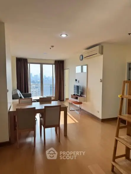 Spacious living room with city view, modern furniture, and wooden flooring in a high-rise apartment.