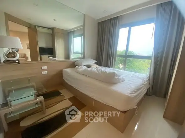 Cozy bedroom with large window and modern furnishings, offering a serene view and ample natural light.