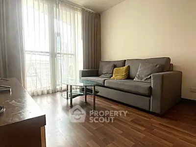 Spacious living room with modern sofa and glass coffee table, featuring floor-to-ceiling windows.