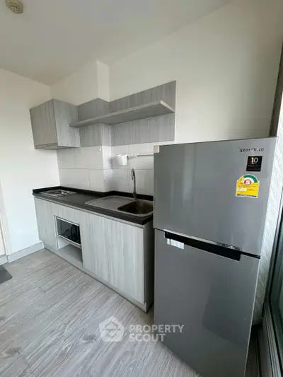 Modern kitchen with sleek cabinetry and stainless steel fridge in a compact layout.