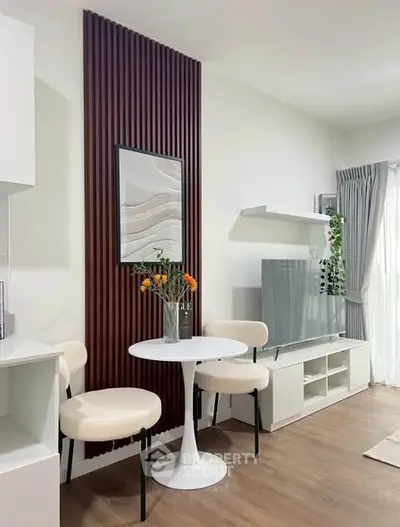 Modern living room with stylish decor and natural light, featuring a cozy seating area and elegant wall art.