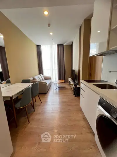 Modern apartment interior with open kitchen and cozy living area, featuring sleek furniture and natural lighting.