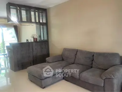 Spacious living room with plush gray sectional sofa and elegant wooden cabinet