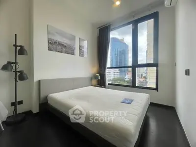 Modern bedroom with large window offering city view, featuring minimalist decor and cozy ambiance.