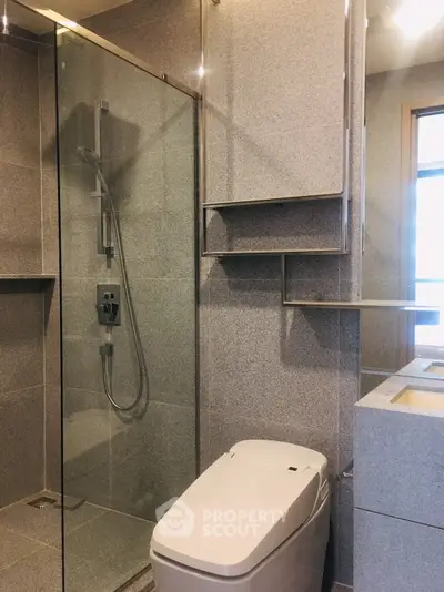 Modern bathroom with sleek design and glass shower enclosure in luxury apartment.