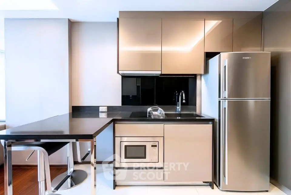 Modern kitchen with sleek cabinetry, stainless steel appliances, and breakfast bar in contemporary apartment.