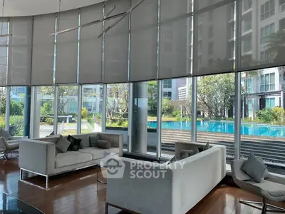 Luxurious modern living room with floor-to-ceiling windows overlooking a stunning pool view.