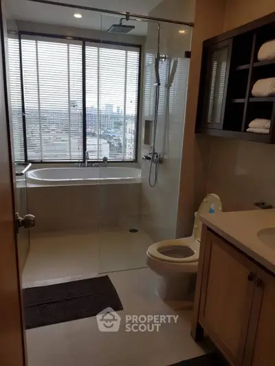 Modern bathroom with city view, featuring a glass shower and bathtub, ideal for urban living.