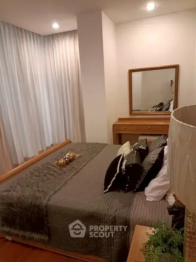 Cozy bedroom with elegant decor and soft lighting, featuring a stylish bed and mirror.