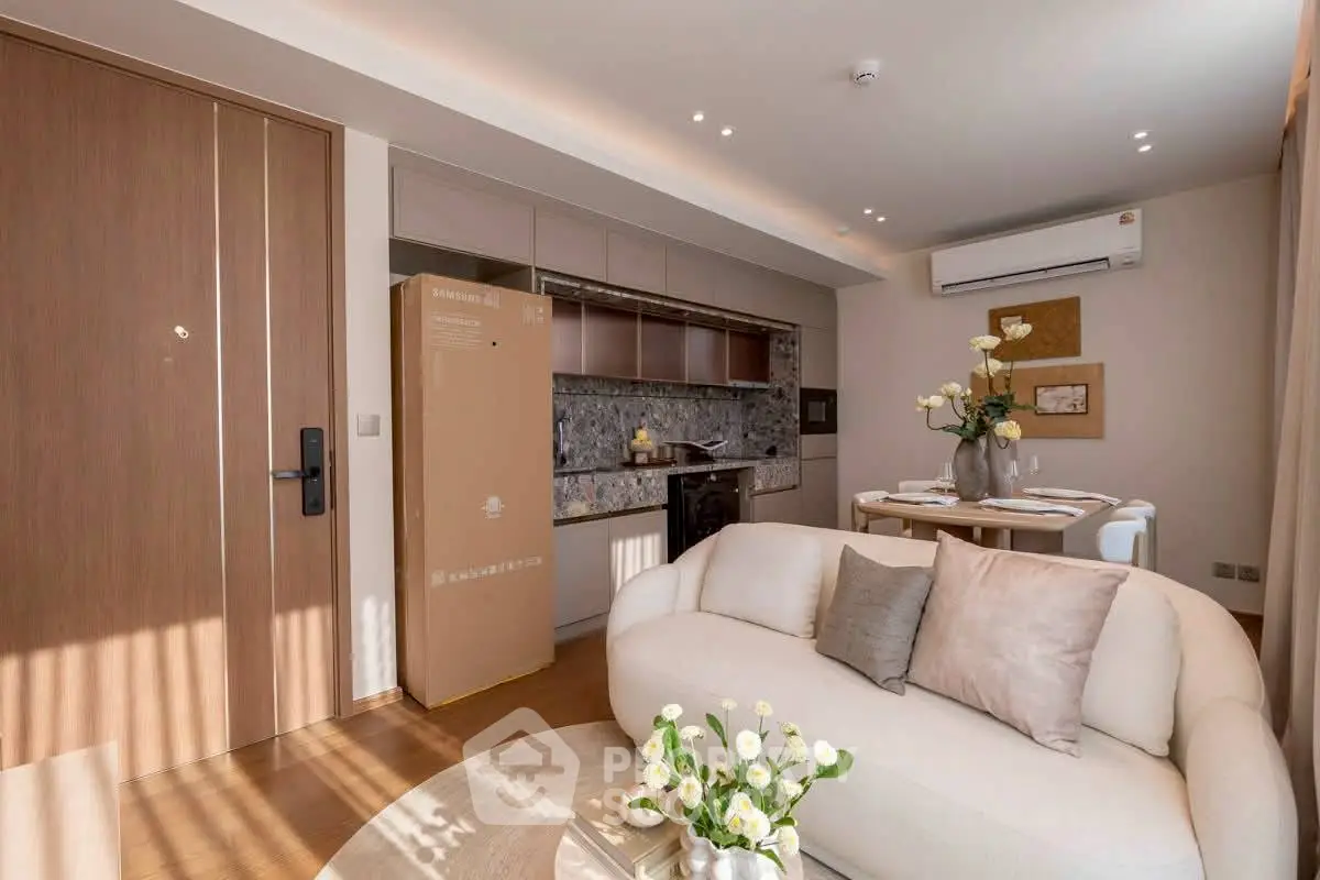 Modern living room with open kitchen, featuring elegant decor and natural light.