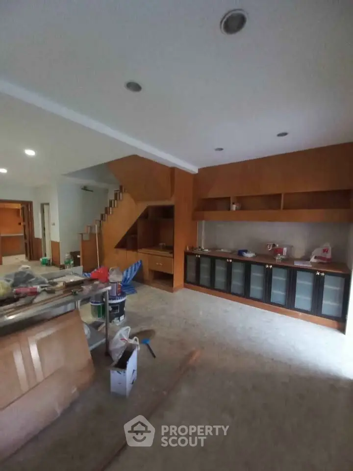 Spacious living room with wooden cabinetry and staircase in modern home