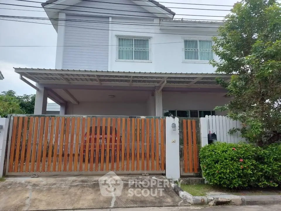 Charming two-story house with gated entrance and lush greenery, perfect for family living.