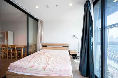 Spacious bedroom with large windows offering ample natural light and city views, seamlessly connected to an open dining area, perfect for modern living.