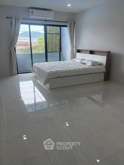 Spacious bedroom with large windows and scenic view, featuring modern air conditioning and elegant tile flooring.