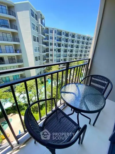 Charming balcony with modern furniture overlooking a vibrant residential complex.