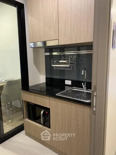 Modern compact kitchen with sleek cabinetry and built-in appliances in a stylish apartment.