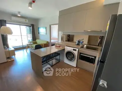 Modern open-plan living room with kitchen featuring washing machine and stylish decor.