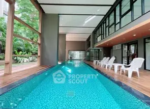 Luxurious indoor pool with modern design and poolside seating in upscale property.