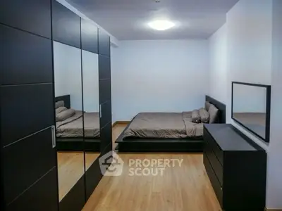 Modern bedroom with sleek black furniture and mirrored wardrobe