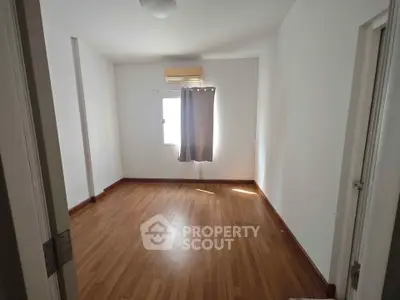 Spacious empty bedroom with wooden flooring and natural light