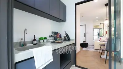 Modern kitchen with sleek cabinetry and open layout leading to stylish living room.