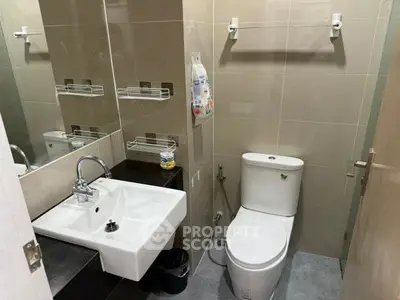 Modern bathroom with sleek fixtures and neutral tiles, featuring a compact design and efficient use of space.