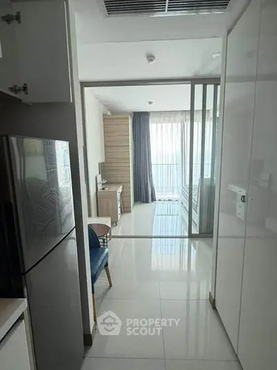 Modern apartment interior with sleek kitchen and bright living area, featuring floor-to-ceiling windows.