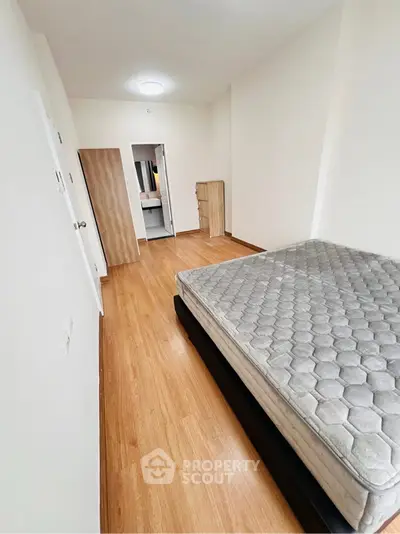 Spacious bedroom with wooden flooring and a comfortable bed frame, ideal for restful nights.