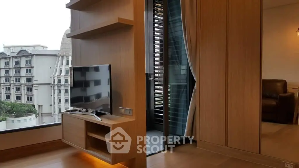 Elegant living space with modern entertainment unit and a glimpse of a spiral staircase, showcasing urban living at its finest.