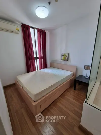 Cozy bedroom with wooden flooring and natural light, featuring a comfortable bed and modern decor.