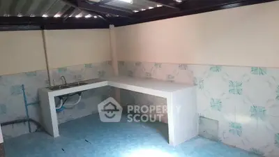 Simple kitchen with tiled walls and floor, featuring a basic sink and countertop.