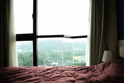 Cozy bedroom with large window offering a scenic view of lush greenery, perfect for relaxation and tranquility.