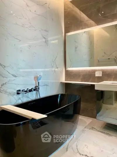 Luxurious modern bathroom with sleek black bathtub and elegant marble walls.