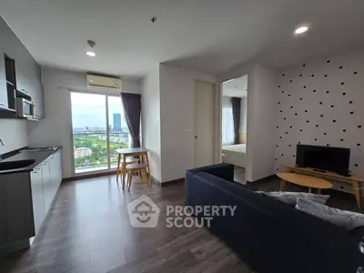 Modern open-plan living room with kitchen and city view, featuring stylish decor and natural light.