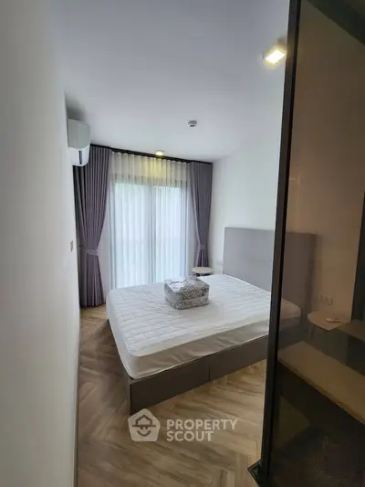 Modern bedroom with elegant curtains and natural light, featuring a cozy bed and stylish flooring.