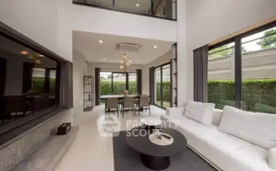 Luxurious modern living room with high ceilings and large windows overlooking a lush garden.
