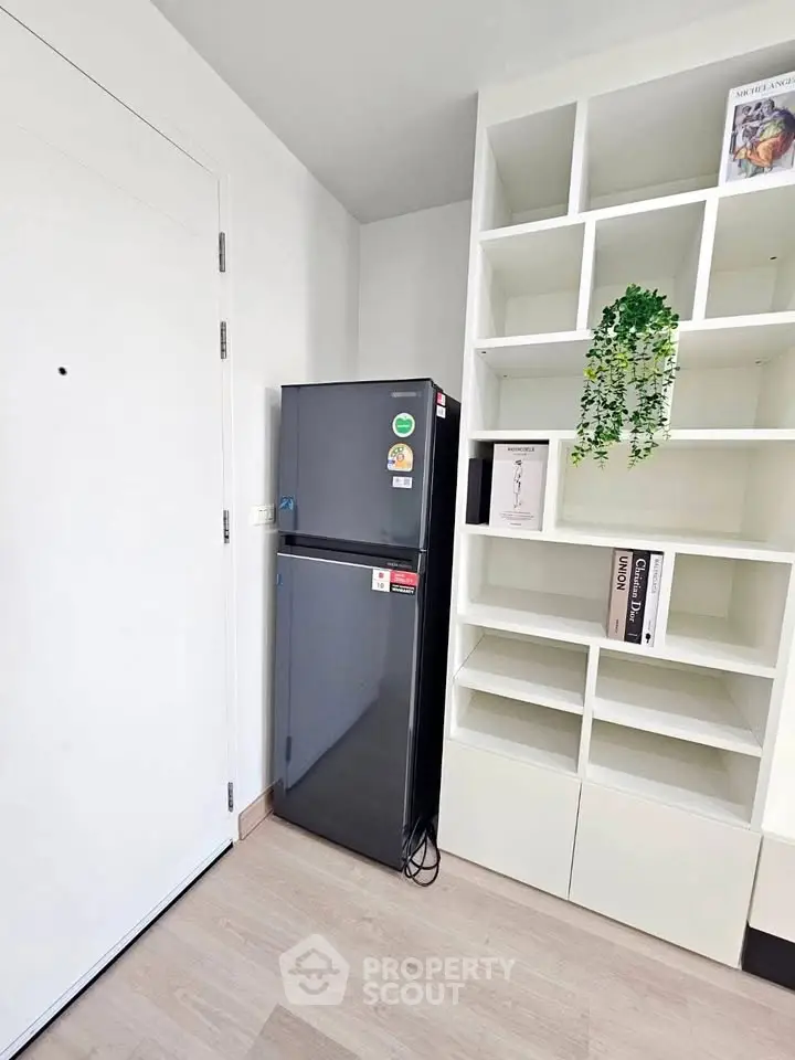Modern kitchen corner with sleek fridge and stylish shelving unit.