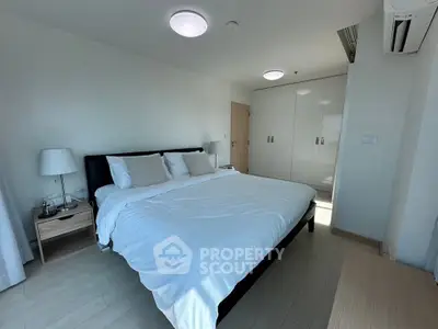 Spacious bedroom with modern furnishings and ample natural light, featuring a large bed and built-in wardrobe.