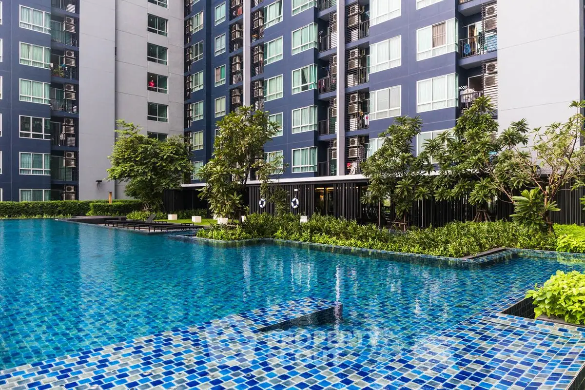 Luxurious condominium with a stunning pool and lush greenery, perfect for modern living.