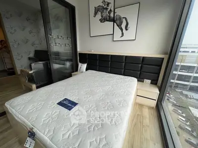 Modern bedroom with stylish decor and large window offering city view, featuring a comfortable bed and elegant artwork.