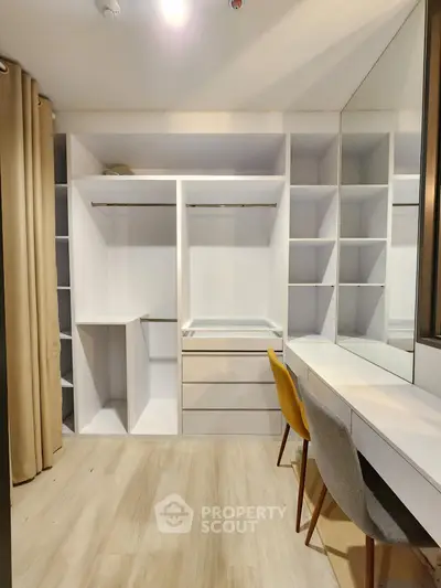 Spacious walk-in closet with modern shelving and mirrored vanity in a stylish home.