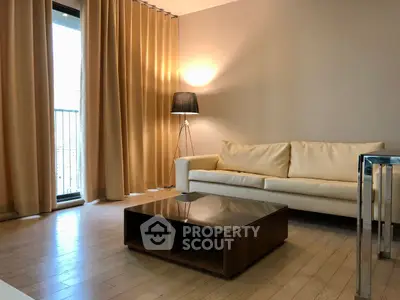 Modern living room with elegant sofa and floor lamp, featuring a sleek coffee table and large window.