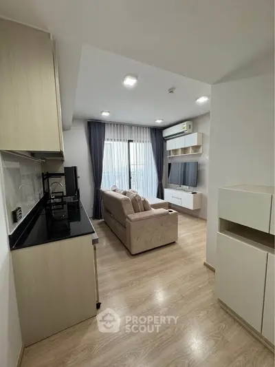 Modern living room with open kitchen, featuring sleek design and natural light.