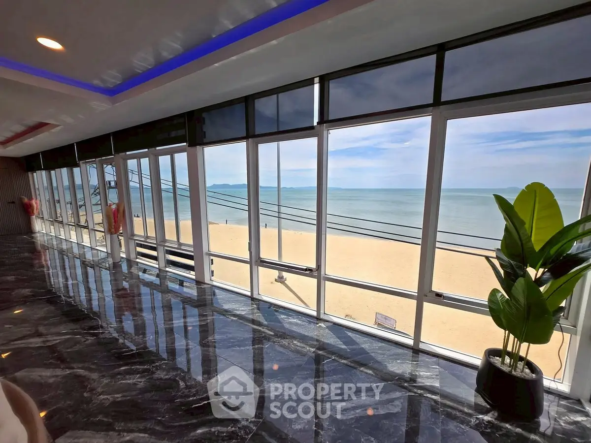 Stunning beachfront view from luxurious modern interior with floor-to-ceiling windows.