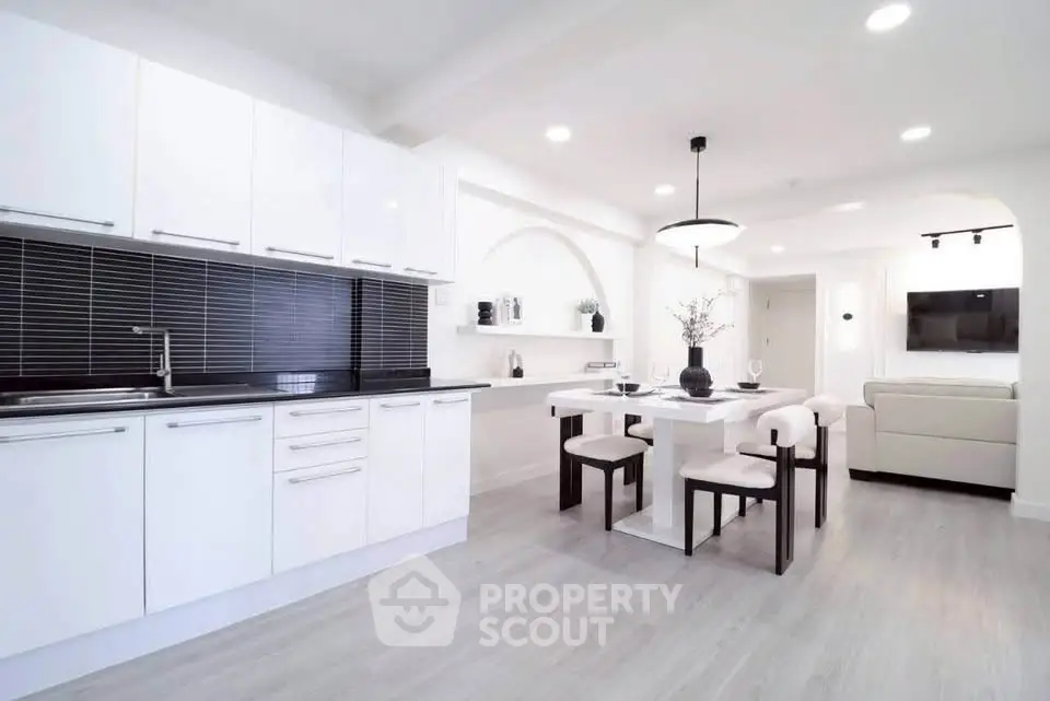 Modern open-layout kitchen and dining area with sleek white cabinets and contemporary decor.