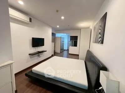 Spacious bedroom with modern decor and wall-mounted TV in a stylish apartment.