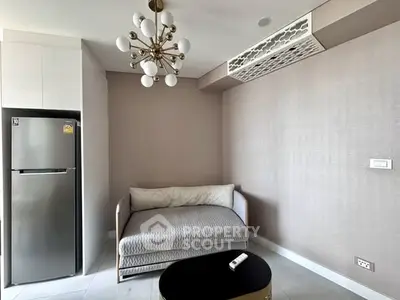 Modern living room with stylish chandelier and cozy sofa, featuring sleek refrigerator and minimalist decor.